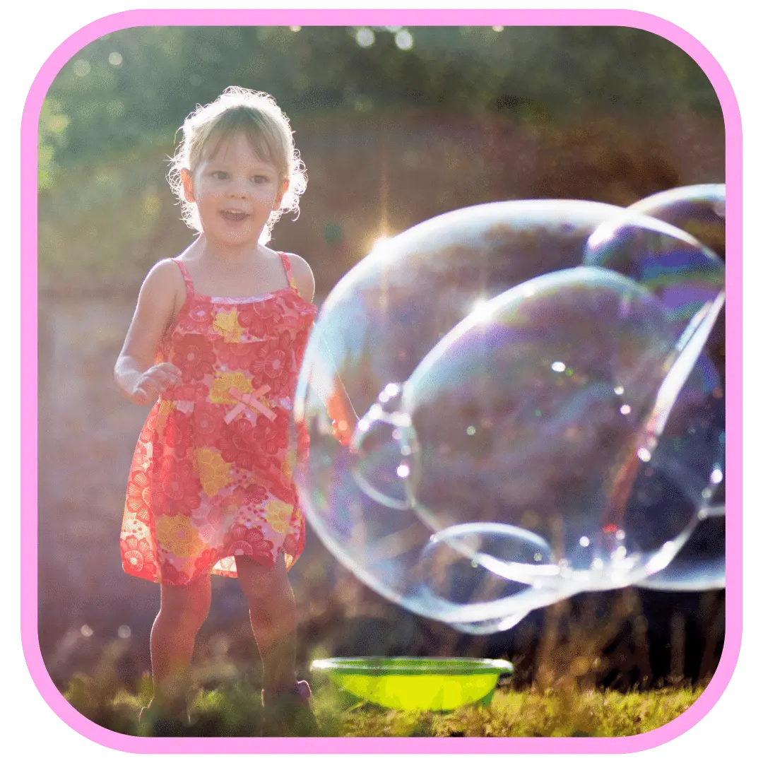 child playing with giant bubbles on her birthday